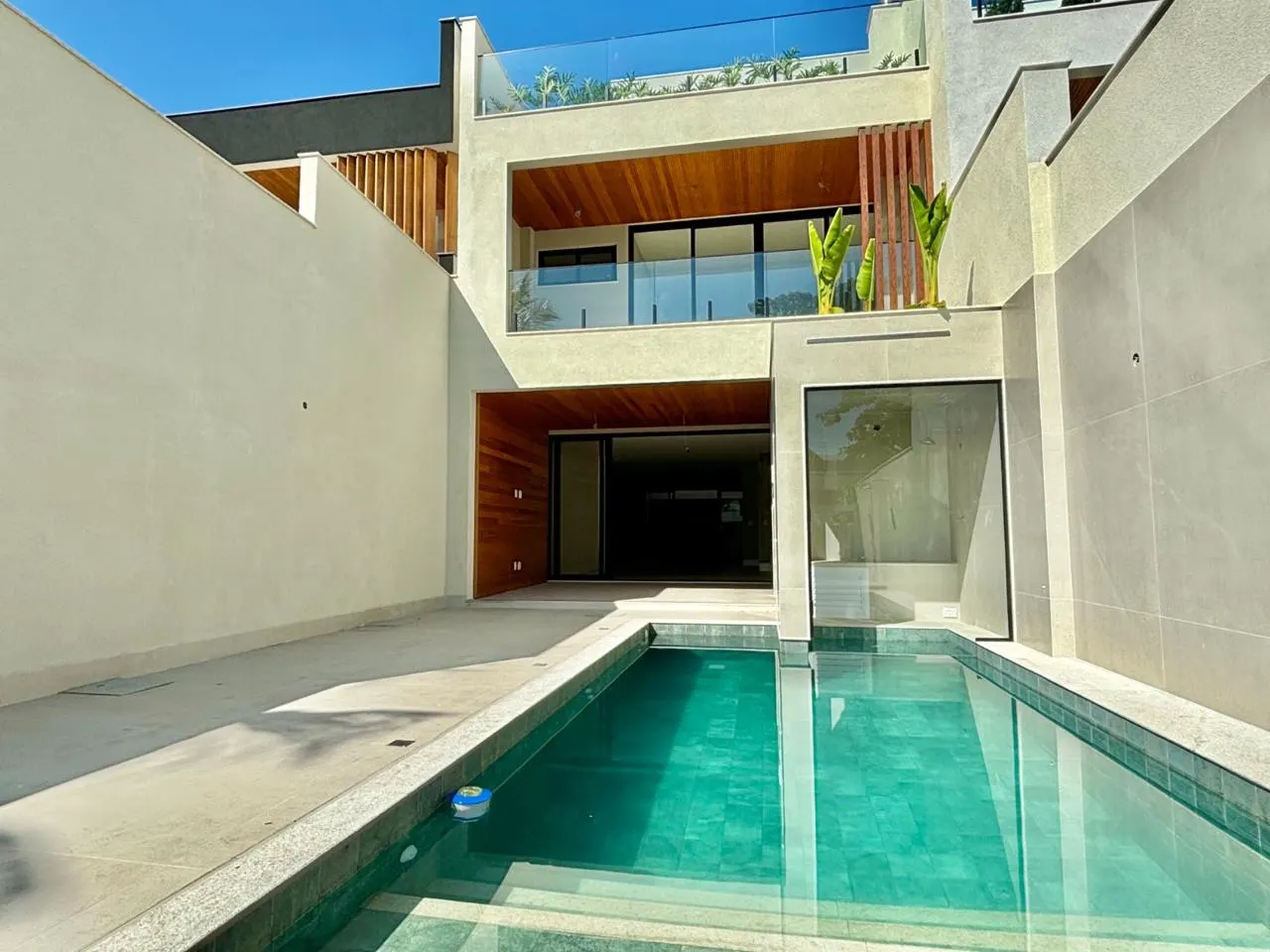 Casa contemporânea entregue pela BRC, com piscina, fachada clara e painéis de madeira
